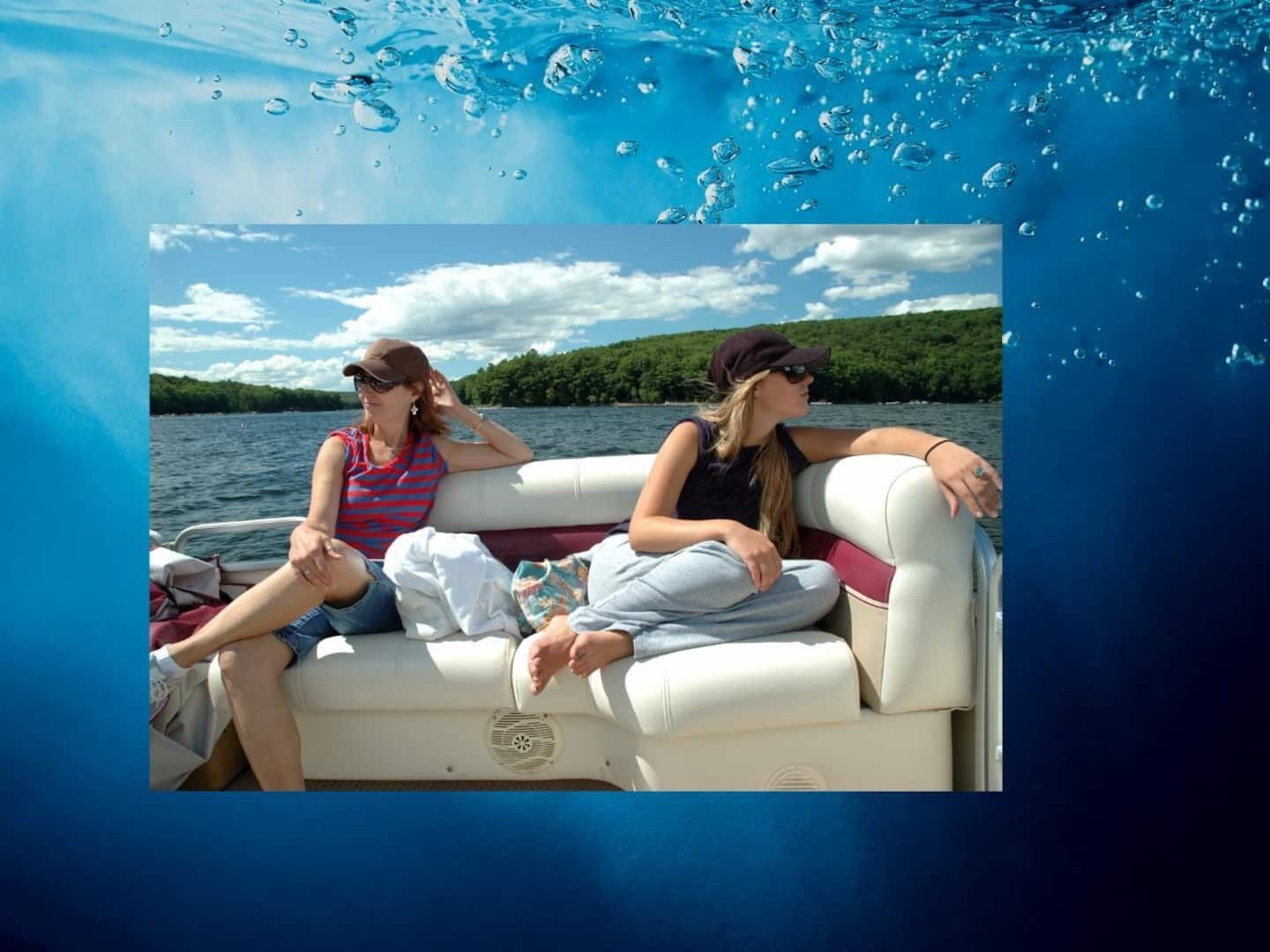 A boat with two people sitting on the deck, surrounded by water and greenery.