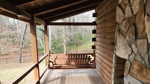 A wooden deck with a stone wall and a bench.