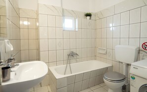 A bathroom with a bathtub, toilet, and sink. - Meteora House with a view (Kalabaka)