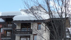 Un immeuble à plusieurs étages, doté de balcons et d’un toit recouvert de neige.