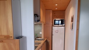 Une cuisine compacte dotée de meubles en bois, d’un four à micro-ondes, d’un réfrigérateur et d’un lave-vaisselle.