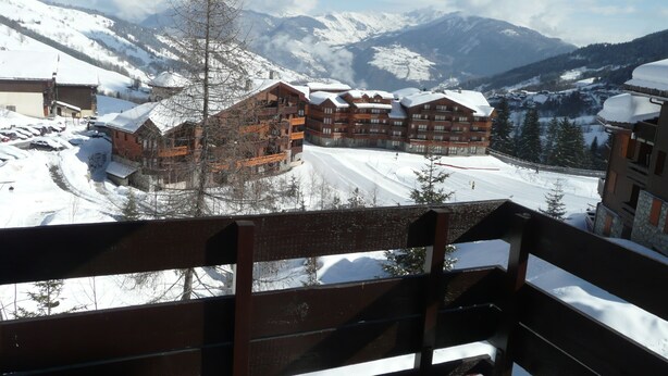 Une station de montagne enneigée, avec des bâtiments en bois et une piste de ski.