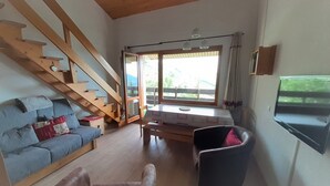 Un salon chaleureux avec un escalier en bois, un canapé, un fauteuil et une table à manger.