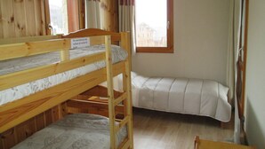 Une pièce avec deux lits superposés, des murs en bois, une fenêtre et un panneau indiquant une limite de hauteur.