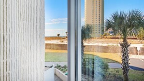 A view from a window overlooking a beach with a tall building in the background.