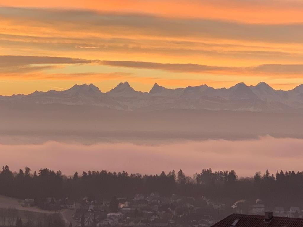 A mountain range at sunrise with a town in the foreground.