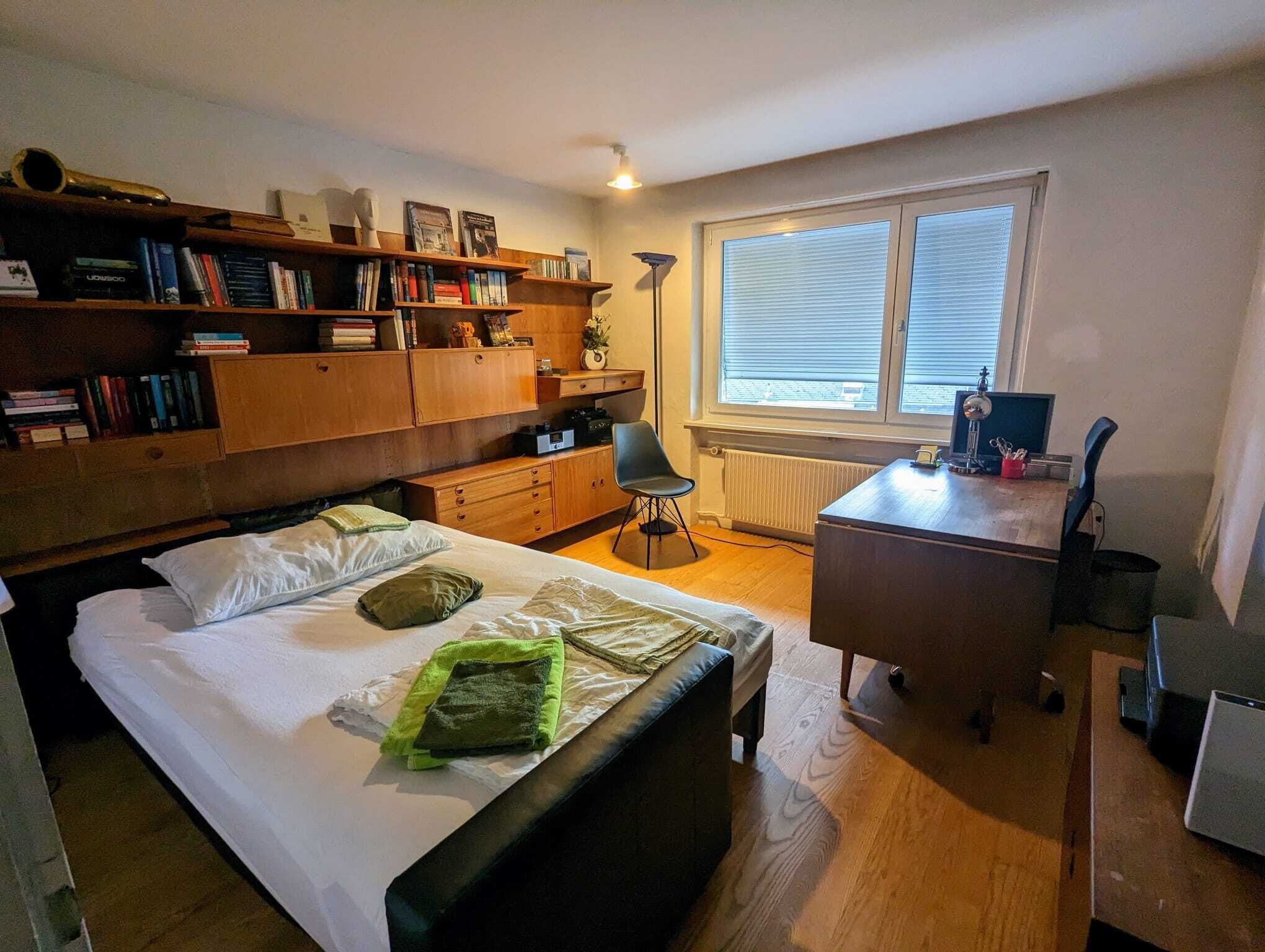 Un dormitorio con cama, escritorio, silla y estantería.