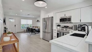 A modern kitchen with white cabinetry, stainless steel appliances, and a large island with a sink. - 5 mins to beach + Brand New Pool and Tiki Hut. (Oakland Park)