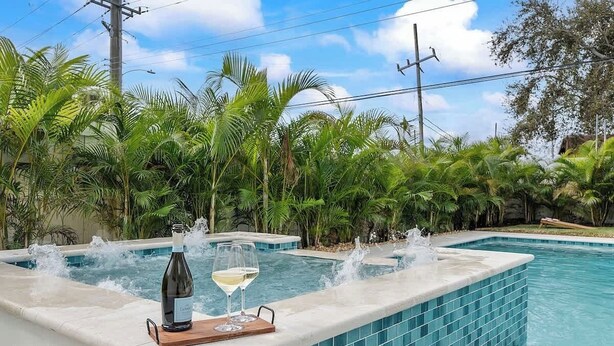 A swimming pool with a jacuzzi area, surrounded by lush tropical plants. - 5 mins to beach + Brand New Pool and Tiki Hut. (Oakland Park)