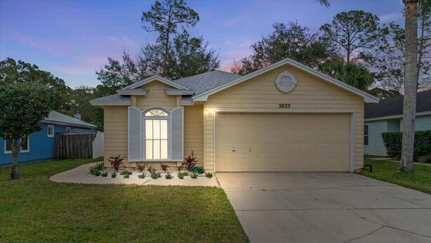 Une maison de plain-pied avec un garage, portant le numéro 3833, et un petit jardin devant la maison, avec une pelouse et quelques plantes.