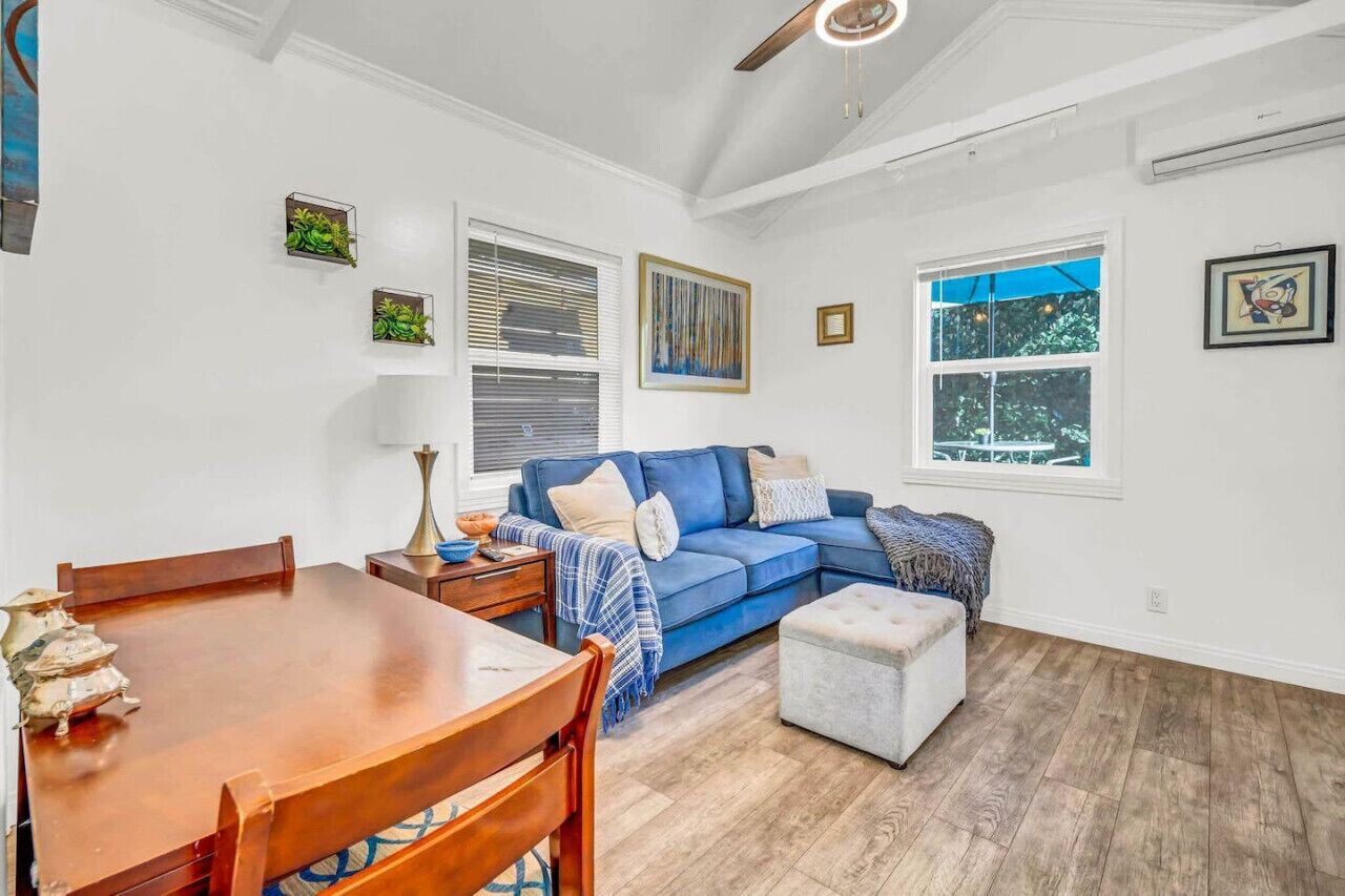 Un salon avec un canapé bleu, une table à manger en bois et un ventilateur de plafond.