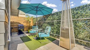 Une terrasse avec un barbecue, des sièges d’extérieur et un parasol décoratif.