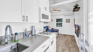 Une cuisine moderne avec des meubles blancs, un évier en acier inoxydable et une cuisinière à gaz.