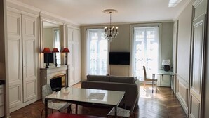Een ruime woonkamer met een open haard, een bank, een eettafel en een televisie.