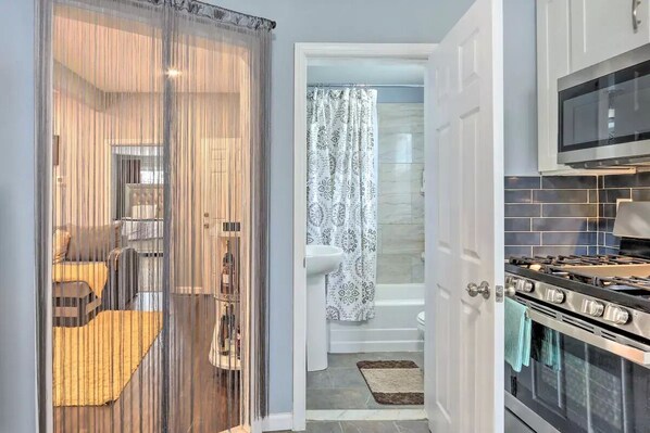 Functional kitchen and bathroom facilities, with a separate sleeping area featuring a bed and chair.
