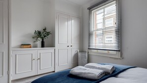 A bedroom with a bed, white wardrobe, and a window with blinds. - Bright Spacious 2-bedroom Jericho House (Oxford)