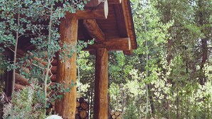 Una cabaña rústica de madera con techo de paja, rodeada de un denso bosque.