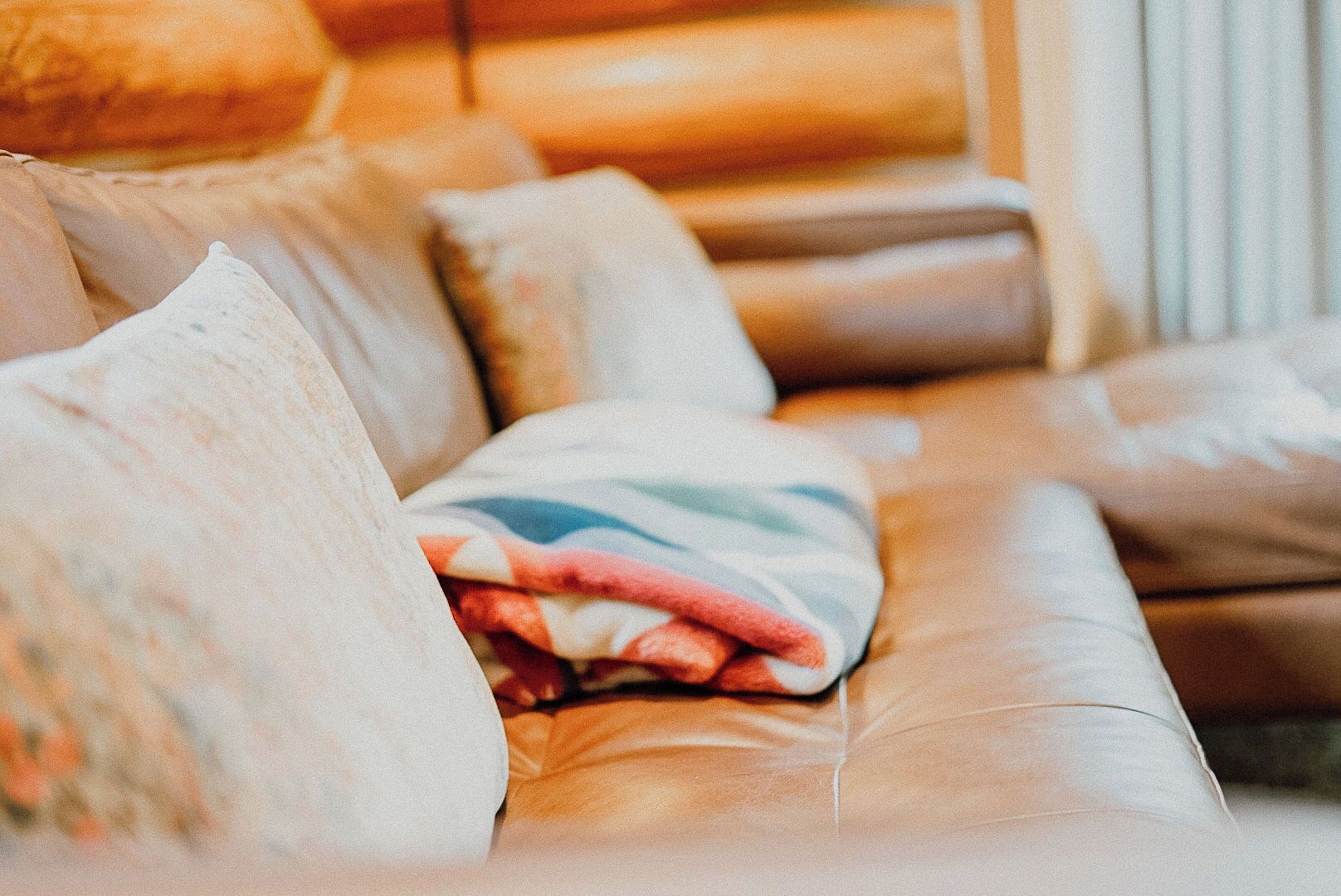 Un canapé en cuir avec plusieurs coussins et une couverture.