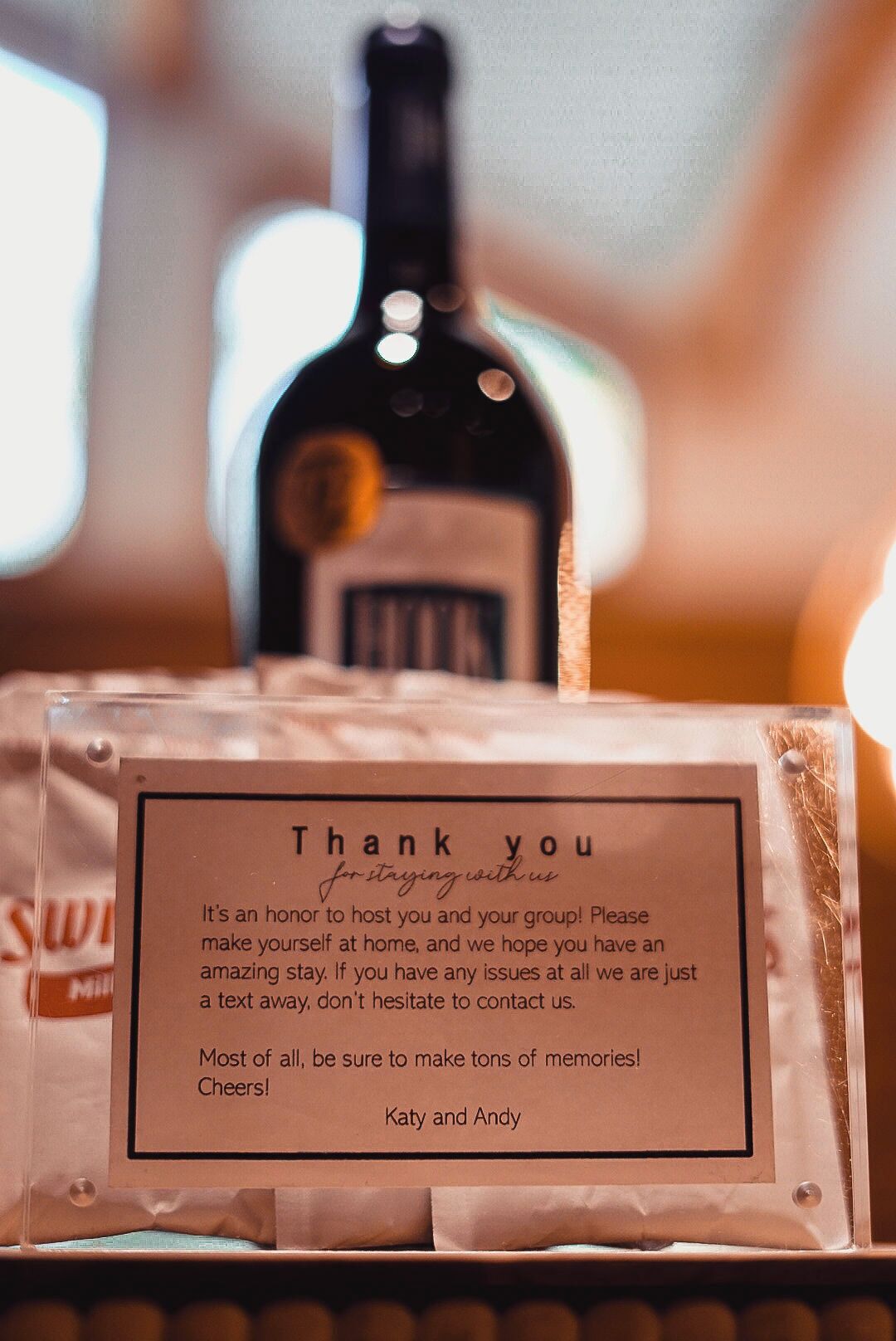 A thank you note card with a message, a bottle of milk, and a clear plastic container.