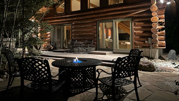 Una cabaña de madera con un patio que cuenta con mobiliario exterior y una chimenea.