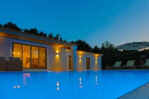 A modern building with a swimming pool, large windows, and outdoor seating.