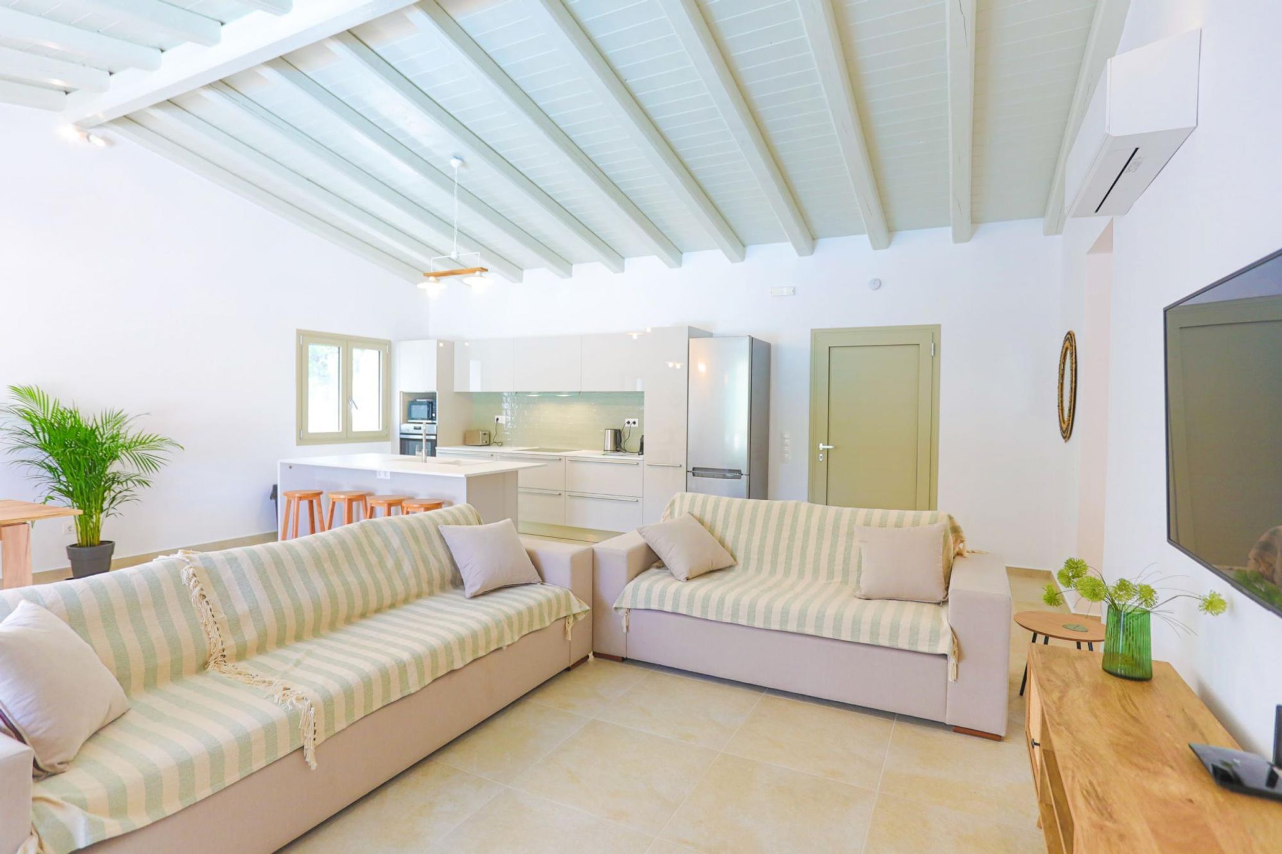 A modern living room with a sofa set, a dining area, and a kitchen in the background.