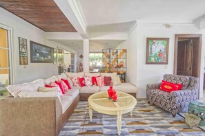 A living room with a sofa, patterned armchair, and a coffee table. - Large Golf View Villa With Pool Jacuzzi and Staff (Punta Cana)