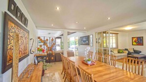 A spacious dining area with a wooden table and chairs, surrounded by walls with abstract art and a decorative metal partition. - Large Golf View Villa With Pool Jacuzzi and Staff (Punta Cana)