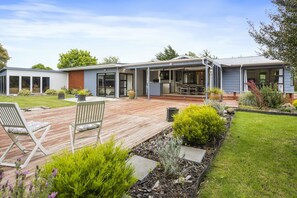 Een modern huis met een overdekt terras, een gazon en een tuin.