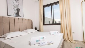 Een hotelkamer met een groot bed, een raam met gordijnen en een schilderij aan de muur.