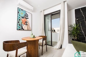 Relax in a serene space with a round table for two, a beautiful abstract art piece, and a sliding door to an outdoor area.