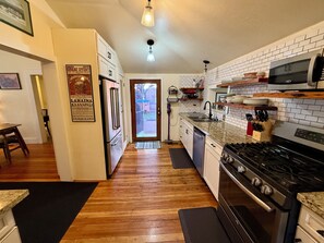 Une cuisine avec des meubles blancs, un réfrigérateur, une cuisinière, un four à micro-ondes et un évier.