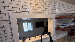 Una cucina con piastrelle bianche a metro, un lavello in acciaio inossidabile, un rubinetto nero e un lampadario.