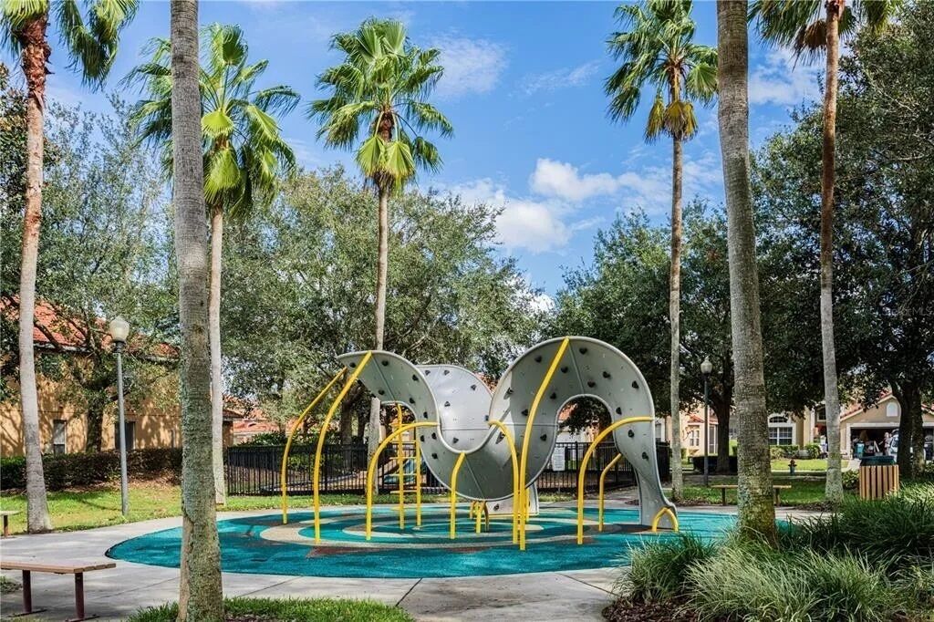 Un parc amb palmeres, una font rodona i una escultura.