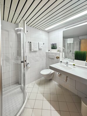 Une salle de bain moderne avec une douche à parois de verre, des toilettes et un lavabo surmonté d’un miroir.