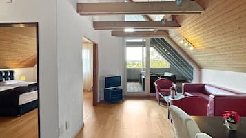 Una habitación amplia con techo de madera, un comedor con mesa y sillas, y vistas a través de un ventanal.