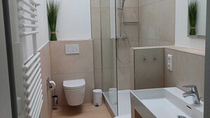 A modern bathroom with a shower, toilet, and sink. - Posthus Apartment 305 with balcony, close to the beach and central (Borkum)