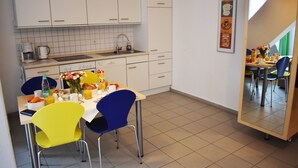 A modern kitchen with white cabinets, a sink, and a dining area with a table and chairs. - Posthus Apartment 305 with balcony, close to the beach and central (Borkum)