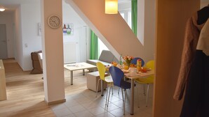 A modern dining area with a table set for two, chairs, and a hanging light fixture. - Posthus Apartment 305 with balcony, close to the beach and central (Borkum)