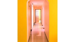 A narrow hallway with a bright yellow wall on one side and a door at the end. - Essy's Furnished Homes Nakuru (Nakuru)