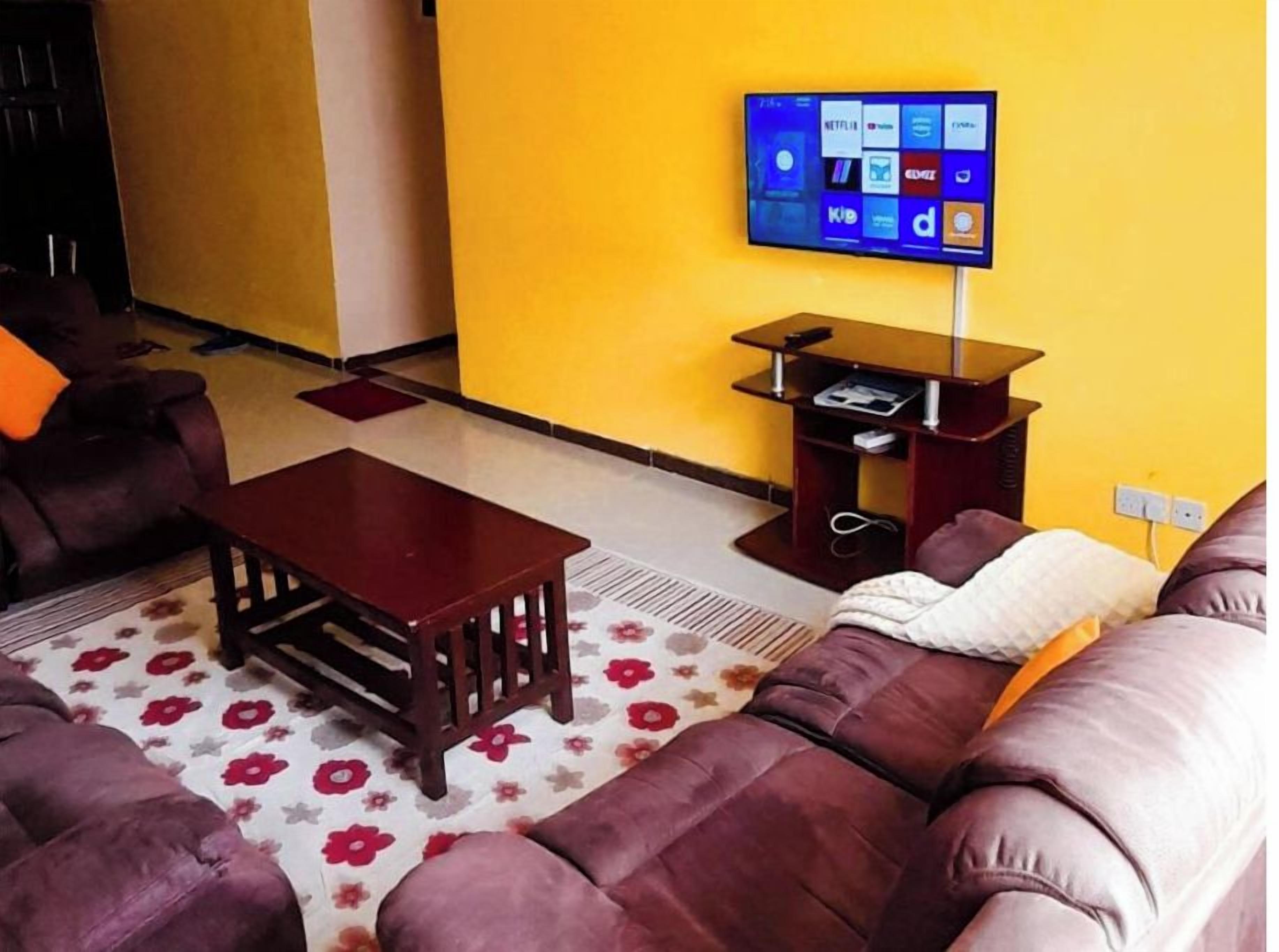 Ein Wohnzimmer mit einer Couch, einem Couchtisch und einem flachbildfernseher an der Wand.