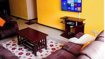 Ein Wohnzimmer mit einer Couch, einem Couchtisch und einem flachbildfernseher an der Wand.