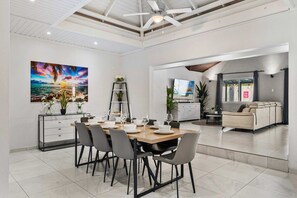 Un vaste espace de vie comprenant une table à manger pour quatre personnes, un canapé et un téléviseur.