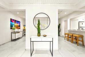 A modern interior with a white console table, a round mirror, and a vibrant painting on the wall. - Stylish 5BR Villa | Salina Sea La Vie | Pool (Noord)