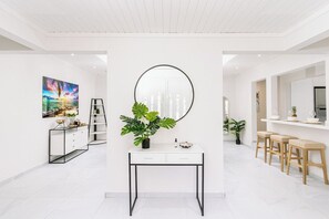 A modern interior with a white console table, a round mirror, a painting, and a plant. - Stylish 5BR Villa | Salina Sea La Vie | Pool (Noord)