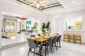 Amplia sala de estar con una mesa de comedor dispuesta para seis personas, rodeada de sillas modernas.