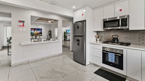 Una cucina moderna con mobili bianchi, elettrodomestici in acciaio inossidabile e pavimento piastrellato.