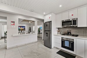 A modern kitchen with white cabinetry, stainless steel appliances, and a tiled floor. - Stylish 5BR Villa | Salina Sea La Vie | Pool (Noord)