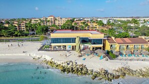 A beachfront hotel with a pool, beach chairs, and a view of the ocean. - Divi Aruba: 3BR Oasis w Free Parking near Beaches (Oranjestad)