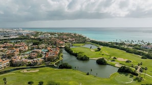 Un campo da golf con una distesa d'acqua, circondato da edifici residenziali e vista sull'oceano.